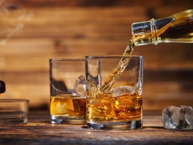 nalievanie whisky do pohára s ľadom